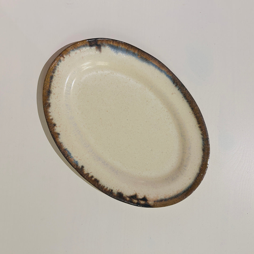 アイボリーベースの青と茶の線が特徴の楕円皿中